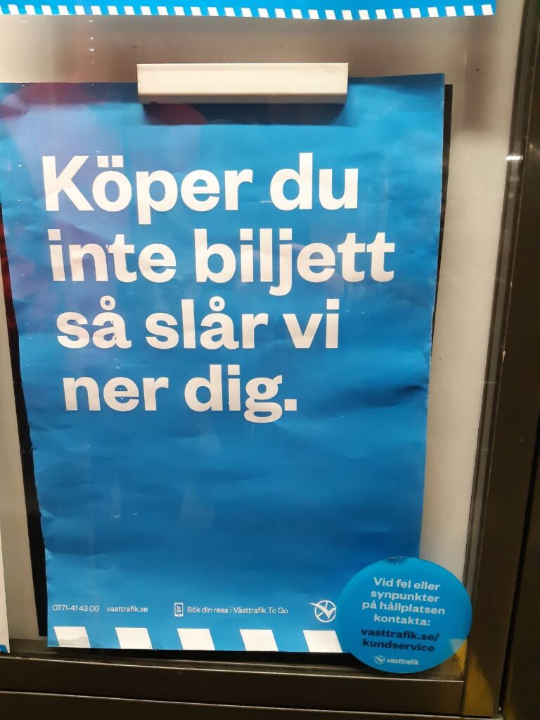 Affisch med västtrafiks grafiska profil som sitter innanför plexiglaset på västtrafiks monter. Texten på affischen lyder: "Köper du inte biljett så slår vi ner dig."

Längst ner på sidan står kontaktinformation till västtrafik. 

Utanpå monterglaset ett klistermärke med texten "Vid fel eller synpunkter på hållplastsen kontakta: västtrafik.se/kundservice"